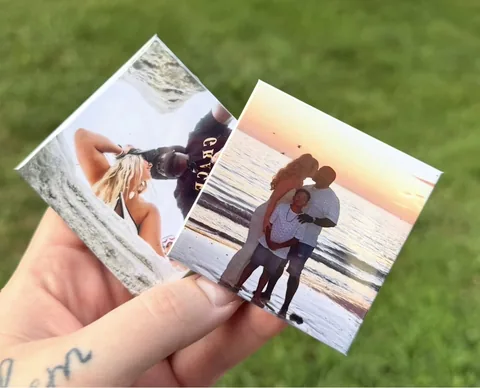 Hand holding two rectangular custom photo magnets outdoors