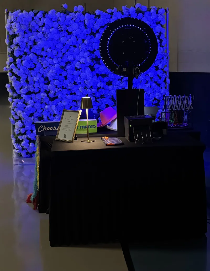 Photo booth setup glowing blue against a floral wall